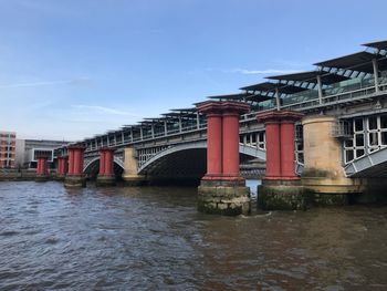 Arch bridge over river against sky in city