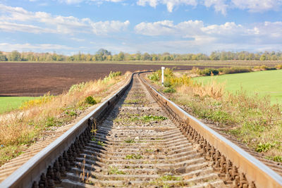 Railroad tracks on field against sky