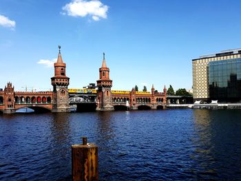 Bridge over river by buildings against sky in city