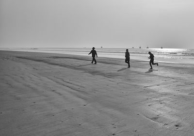 People on beach against clear sky