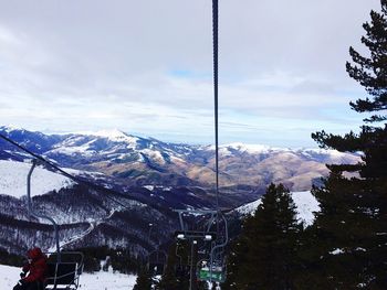 Ski lift by mountains against sky