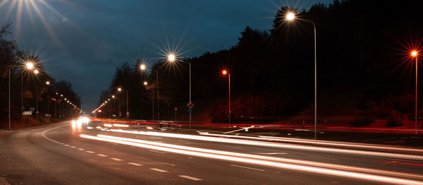 Light trails on road against sky at night