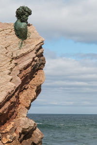 Rock formation by sea against sky