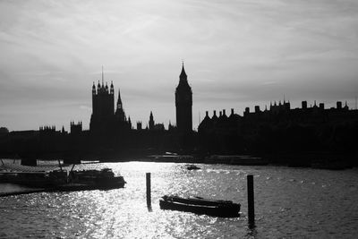 Big ben by thames river against sky in city