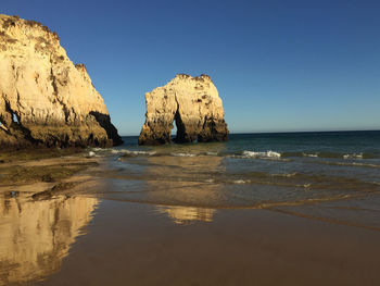 Rock formation on beach against clear sky