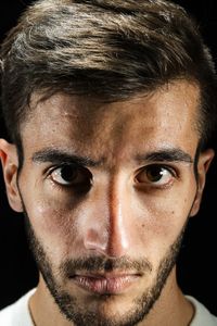 Close-up portrait of young man against black background