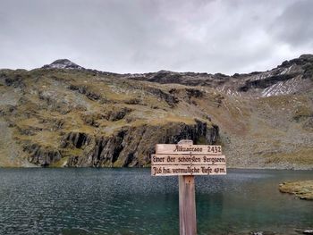 Information sign by mountain against sky