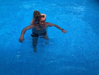 High angle view of father and daughter swimming in pool