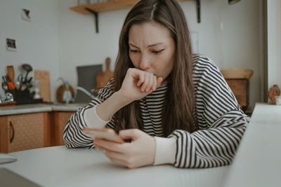 Young woman using mobile phone at home