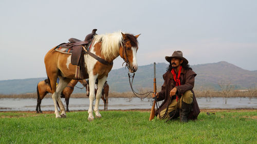 Man with horses on field against sky