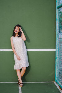 Portrait of a smiling young woman standing against wall