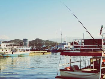 Boats moored at harbor against clear sky