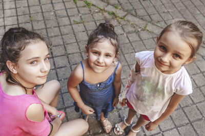 Three smiling little girls look into the camera outdoors