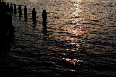 Reflection of wooden post in sea