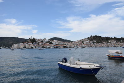 Boats moored in sea by buildings against sky