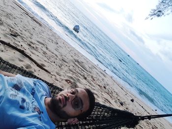 Young woman relaxing on beach against sky