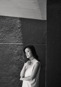 Portrait of young woman standing against wall