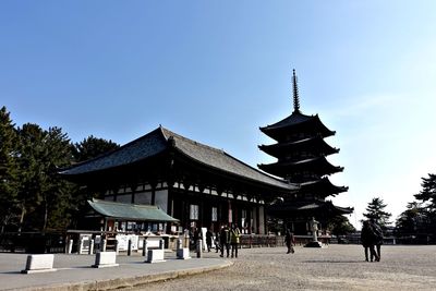 People at temple against clear sky