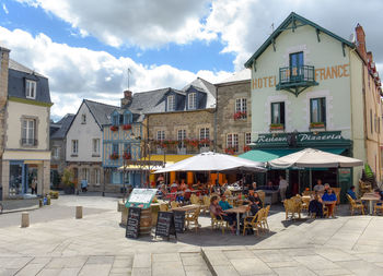 People on sidewalk cafe by buildings in city