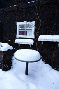 Snow covered empty table and bare trees on field during winter