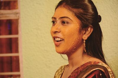 Portrait of smiling young woman against wall