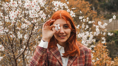 Happy red-haired girl under spring flower tree. spring mood.