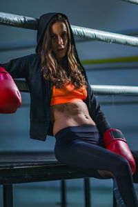 Portrait of female boxer sitting on boxing ring