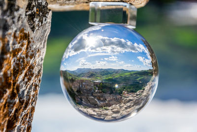 Close-up of crystal ball on glass against trees