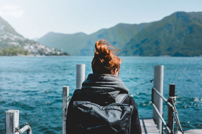 Rear view of woman standing by sea against mountain