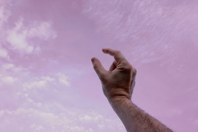 Low angle view of human hand against sky