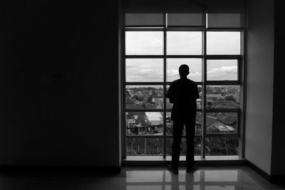 Silhouette of man in front of window