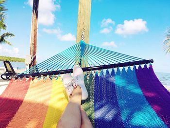 Low section of woman relaxing in hammock against sky
