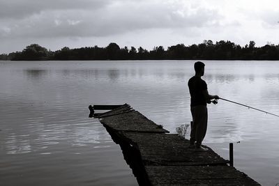 Rear view of man fishing on pier