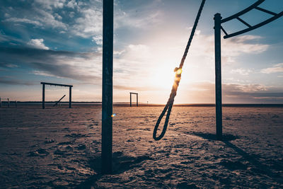 Wooden posts on beach against sky during sunset