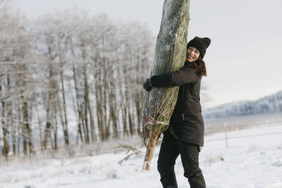 Woman carrying christmas tree at winter