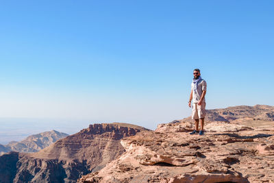 Man standing on rock against clear sky