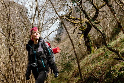 Smiling woman with arms raised in forest