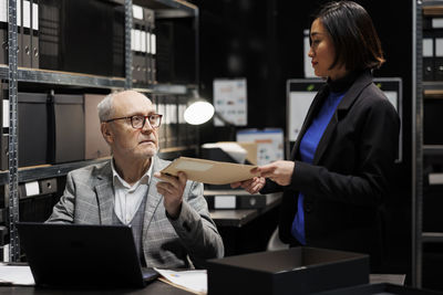 Portrait of woman using laptop while standing in office