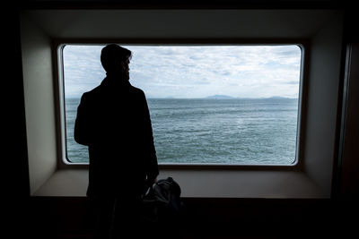 Man looking through window at sea