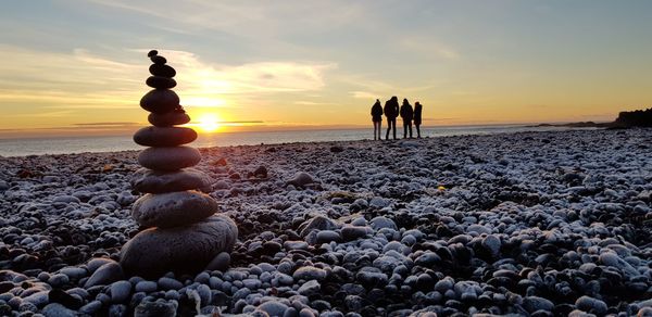 Rocks on beach against sky during sunset