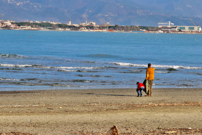 Rear view of people on beach against sky