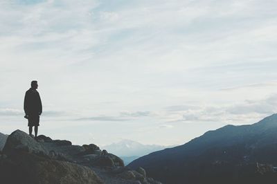 Man standing on mountain against cloudy sky