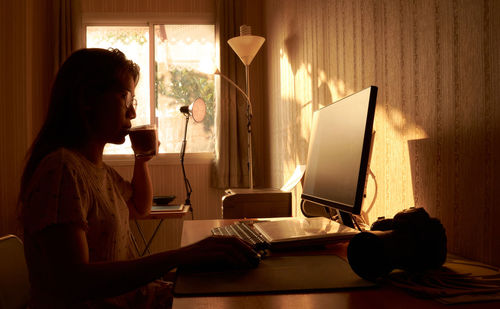 A woman drinks from cup white working from home