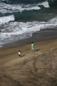 High angle view of father with son fishing at beach