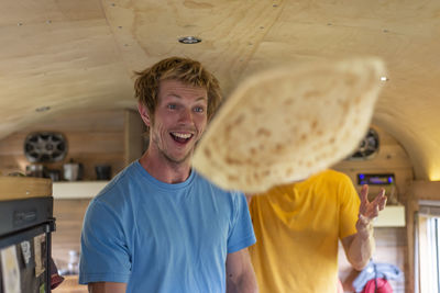 Two people making funny face while flipping crepes inside school bus