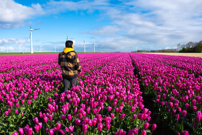 Rear view of woman walking on field against sky