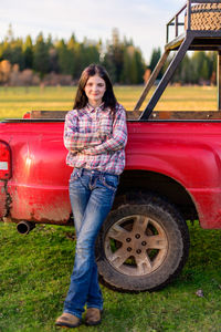 Portrait of young woman leaning against truck 