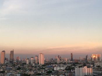 Modern buildings in city against sky during sunset