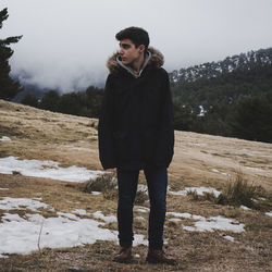 Full length of man looking away while standing on field during winter