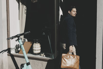 Businessman holding laptop bag while arriving at office